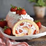 Soft sponge cake roll filled with fresh strawberries and whipped cream, dusted with powdered sugar.