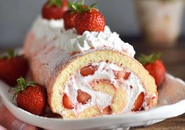 Soft sponge cake roll filled with fresh strawberries and whipped cream, dusted with powdered sugar.