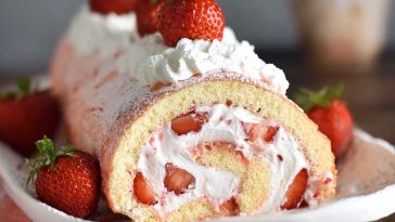 Soft sponge cake roll filled with fresh strawberries and whipped cream, dusted with powdered sugar.