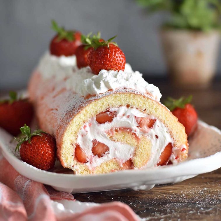 Soft sponge cake roll filled with fresh strawberries and whipped cream, dusted with powdered sugar.