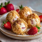 Mini strawberry cheesecake crunch bites topped with fresh strawberries and golden cookie crumbles, arranged on a serving tray.