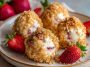 Mini strawberry cheesecake crunch bites topped with fresh strawberries and golden cookie crumbles, arranged on a serving tray.