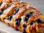 Flaky pastry braid filled with blueberry compote and cream cheese, baked golden and drizzled with icing.