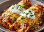 Creamy chicken enchiladas baked with melted cheese and rich sauce in a casserole dish.