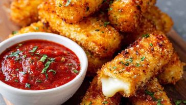 Crispy mozzarella sticks with marinara dipping sauce on a plate