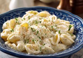 A creamy bowl of fettuccine pasta topped with cottage cheese Alfredo sauce, garnished with fresh parsley and grated Parmesan.