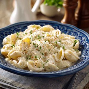 A creamy bowl of fettuccine pasta topped with cottage cheese Alfredo sauce, garnished with fresh parsley and grated Parmesan.