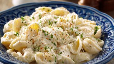A creamy bowl of fettuccine pasta topped with cottage cheese Alfredo sauce, garnished with fresh parsley and grated Parmesan.