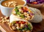 Fresh Thai peanut chicken wraps filled with grilled chicken, crunchy vegetables, and drizzled with creamy peanut sauce, served on a wooden board.