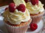 Fluffy raspberry lemon cupcakes topped with creamy frosting, fresh raspberries, and a drizzle of lemon glaze, arranged on a dessert stand.