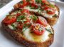 Toasted bread topped with fresh tomatoes, mozzarella cheese, and basil leaves, drizzled with olive oil.