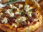 Crispy pizza topped with sausage, ricotta cheese, melted cheese, and drizzled with hot honey.