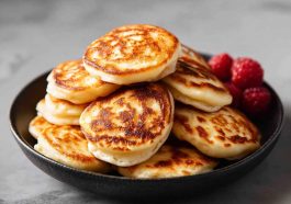 Stack of fluffy mini pancakes topped with berries and syrup