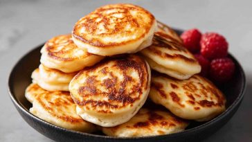 Stack of fluffy mini pancakes topped with berries and syrup