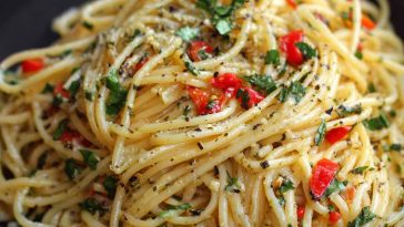 A rustic plate of Italian pasta tossed in garlic olive oil sauce, garnished with fresh parsley and Parmesan cheese, served with crusty bread.