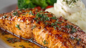 Grilled salmon fillet glazed with a sweet and savory sauce, served with lemon and herbs.