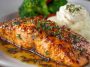 Grilled salmon fillet glazed with a sweet and savory sauce, served with lemon and herbs.