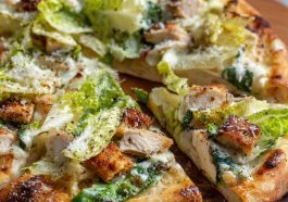 Chicken Caesar salad pizza topped with grilled chicken, romaine lettuce, parmesan cheese, and creamy dressing.