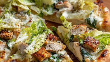 Chicken Caesar salad pizza topped with grilled chicken, romaine lettuce, parmesan cheese, and creamy dressing.