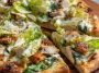 Chicken Caesar salad pizza topped with grilled chicken, romaine lettuce, parmesan cheese, and creamy dressing.