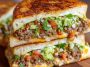 Toasted sandwich filled with seasoned ground beef, melted cheese, and fresh toppings.