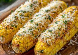 Grilled corn on the cob coated in garlic butter and sprinkled with grated parmesan cheese and herbs.