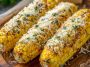 Grilled corn on the cob coated in garlic butter and sprinkled with grated parmesan cheese and herbs.
