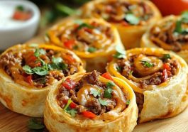 Taco pinwheels made with tortillas filled with seasoned meat, cheese, and vegetables, sliced into bite-sized rolls.