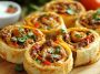 Taco pinwheels made with tortillas filled with seasoned meat, cheese, and vegetables, sliced into bite-sized rolls.