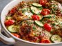 A baked Mediterranean chicken and zucchini casserole topped with melted cheese, fresh herbs, and served in a rustic dish.