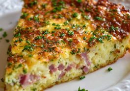 A golden-brown hash brown crust quiche filled with ham, sharp cheddar cheese, and eggs, sliced and served on a rustic plate.