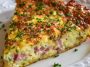 A golden-brown hash brown crust quiche filled with ham, sharp cheddar cheese, and eggs, sliced and served on a rustic plate.