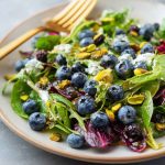 Fresh blueberry pistachio spring salad with mixed greens, vibrant berries, and crunchy nuts.