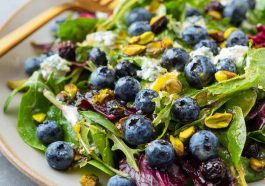 Fresh blueberry pistachio spring salad with mixed greens, vibrant berries, and crunchy nuts.