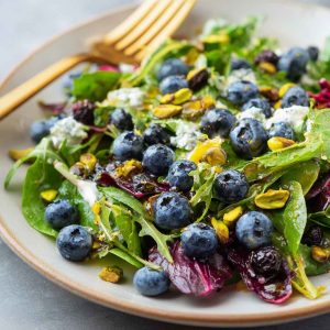 Fresh blueberry pistachio spring salad with mixed greens, vibrant berries, and crunchy nuts.