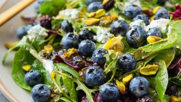 Fresh blueberry pistachio spring salad with mixed greens, vibrant berries, and crunchy nuts.