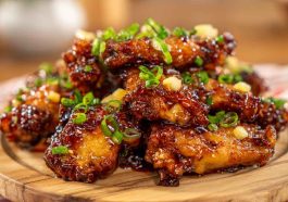 Sticky pineapple cowboy candy chicken wings glazed with sweet and spicy sauce, garnished with peppers.