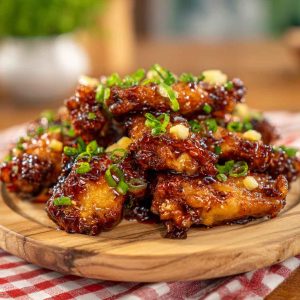 Sticky pineapple cowboy candy chicken wings glazed with sweet and spicy sauce, garnished with peppers.