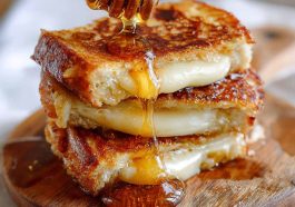 Hot honey grilled cheese sandwich with melted cheese and a drizzle of spicy honey between crispy golden bread.