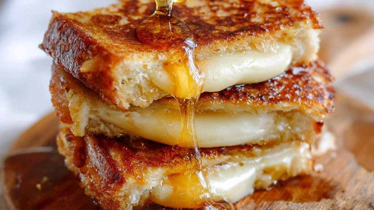 Hot honey grilled cheese sandwich with melted cheese and a drizzle of spicy honey between crispy golden bread.