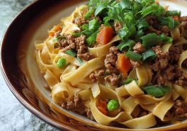 Ground pork stir-fry with flat noodles, vegetables, and a savory sauce in a wok.