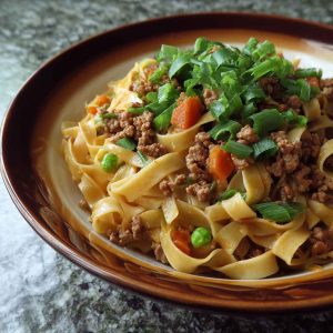 Ground pork stir-fry with flat noodles, vegetables, and a savory sauce in a wok.