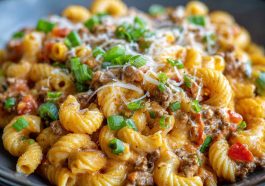 A bowl of creamy Rotel pasta with ground beef, topped with melted cheese and garnished with fresh parsley, served hot and comforting.