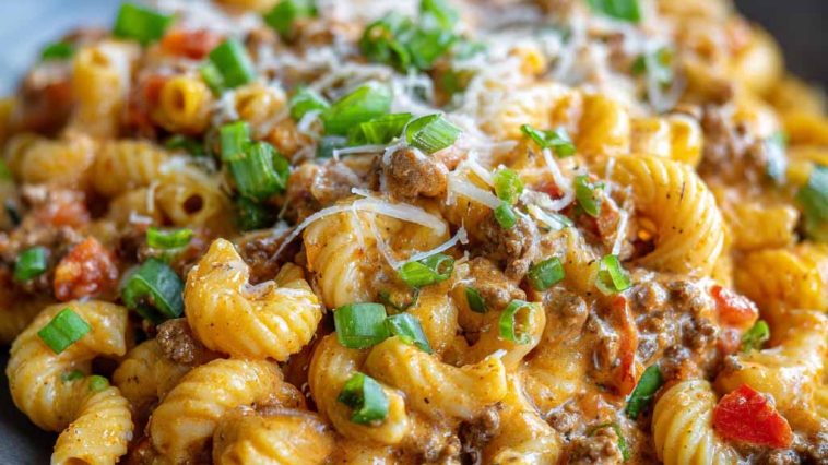 A bowl of creamy Rotel pasta with ground beef, topped with melted cheese and garnished with fresh parsley, served hot and comforting.