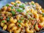 A bowl of creamy Rotel pasta with ground beef, topped with melted cheese and garnished with fresh parsley, served hot and comforting.