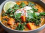 A hearty bowl of ginger sweet potato and coconut milk stew with lentils and kale, garnished with fresh herbs and served warm in a rustic dish.