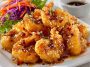 Crispy shrimp coated in a creamy honey sauce, garnished with sesame seeds and herbs.