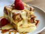 Warm custard bread pudding baked until golden, topped with powdered sugar and served with a creamy sauce.