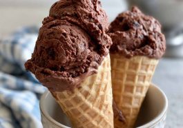 Creamy brownie batter ice cream scooped into a bowl with chocolate brownie chunks and chocolate drizzle on top.
