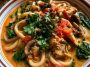 Thai-inspired coconut red curry chicken udon in a bowl with creamy sauce, tender chicken, chewy udon noodles, and fresh herbs on top.